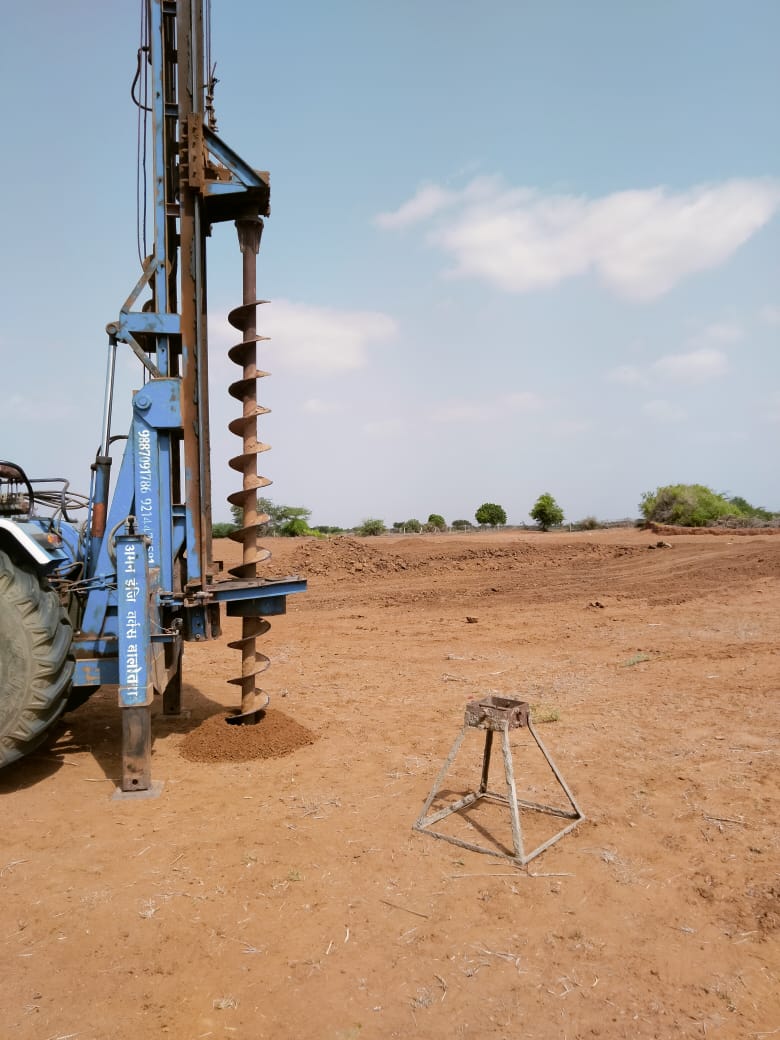 Hydraulic auger rig boring foundation holes in red site soil